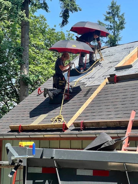 Roofers working on a roof under SunSafe Shield umbrella shades